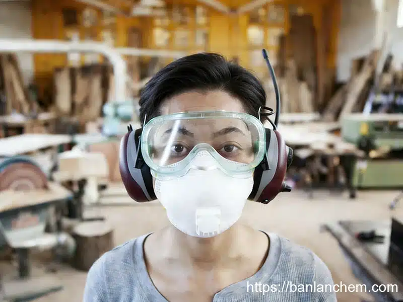 industrial worker wearing mask and safety goggles handling aluminum hydroxide ATH powder to reduce dust inhalation and eye irritation